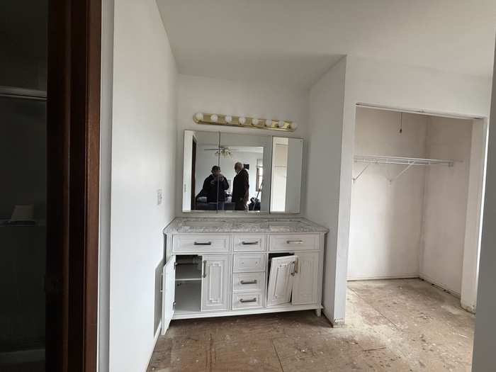 Before: dated double vanity, tri-fold mirror and brass light bar in a Wheaton, IL primary bathroom before remodeling by Goodman Painters & Decorators